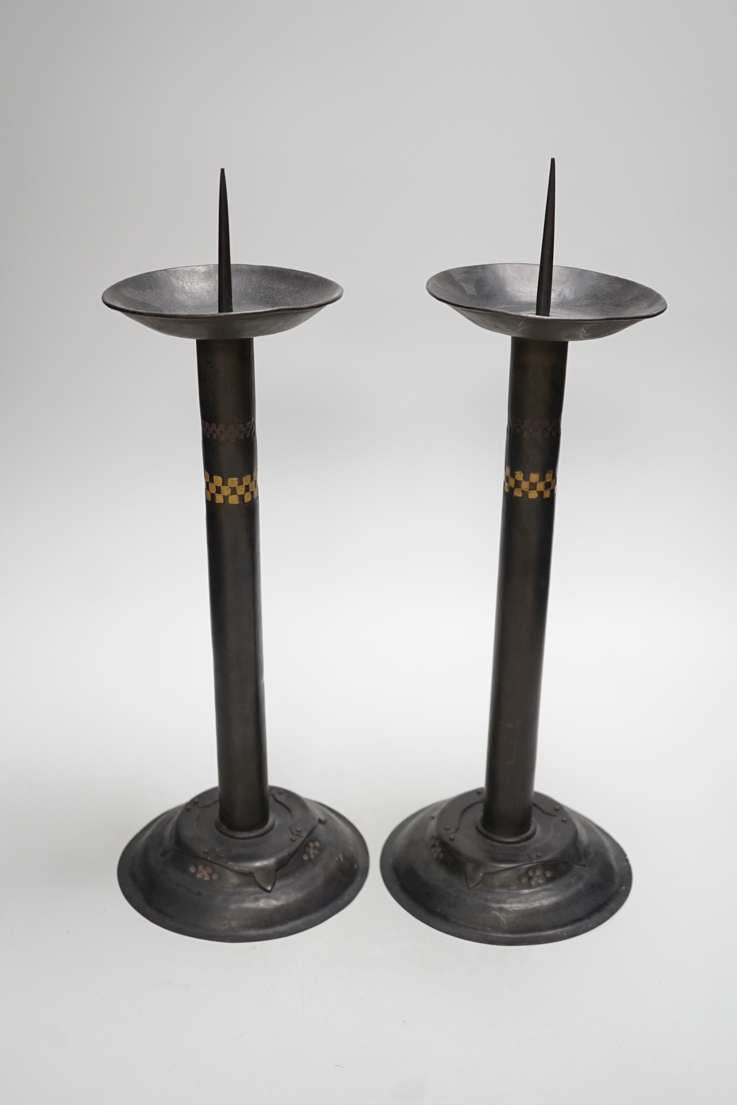 Attributed to Glasgow School of Art - a pair of Arts and Crafts pricket candlesticks. 40cm tall